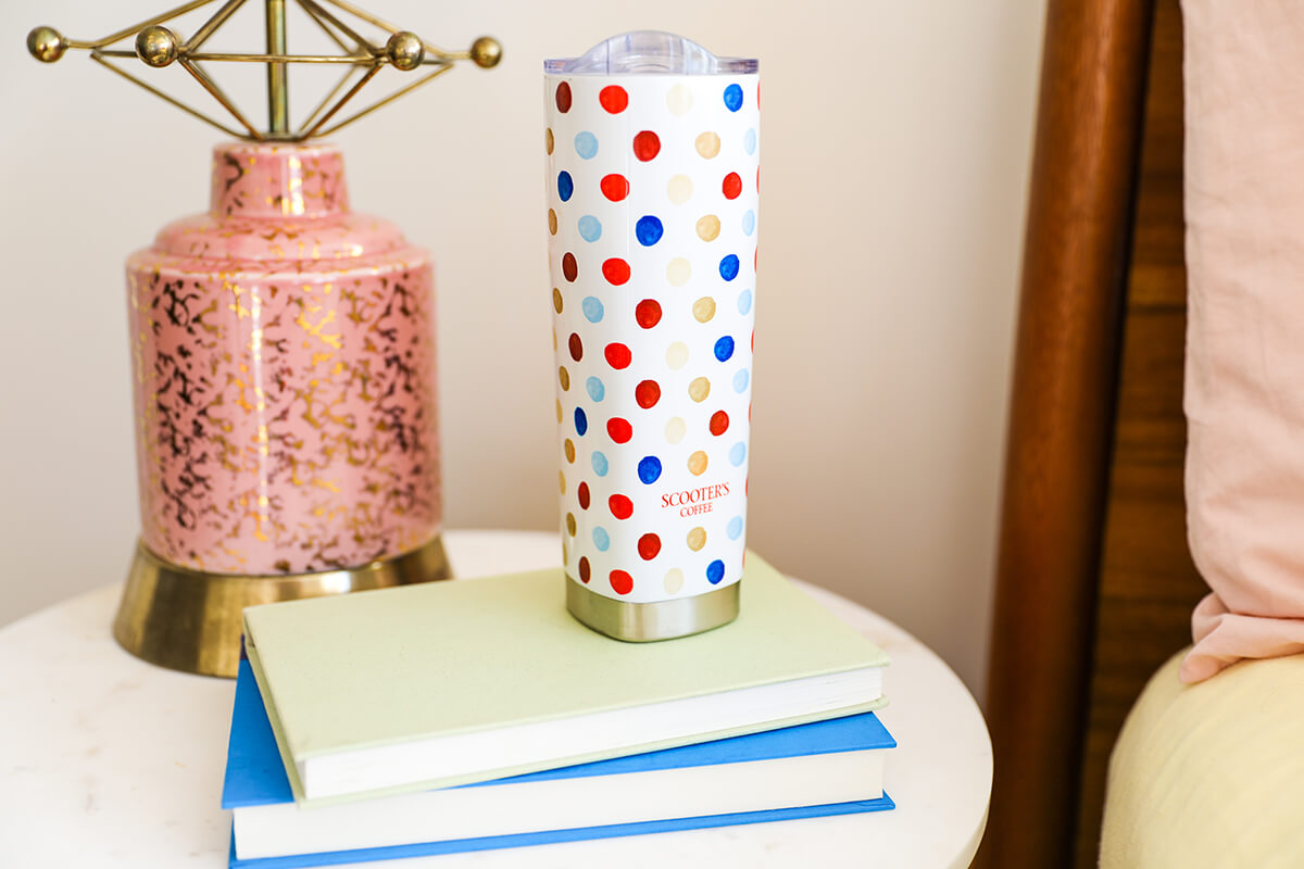 White tumbler with polka dots sitting on top of books