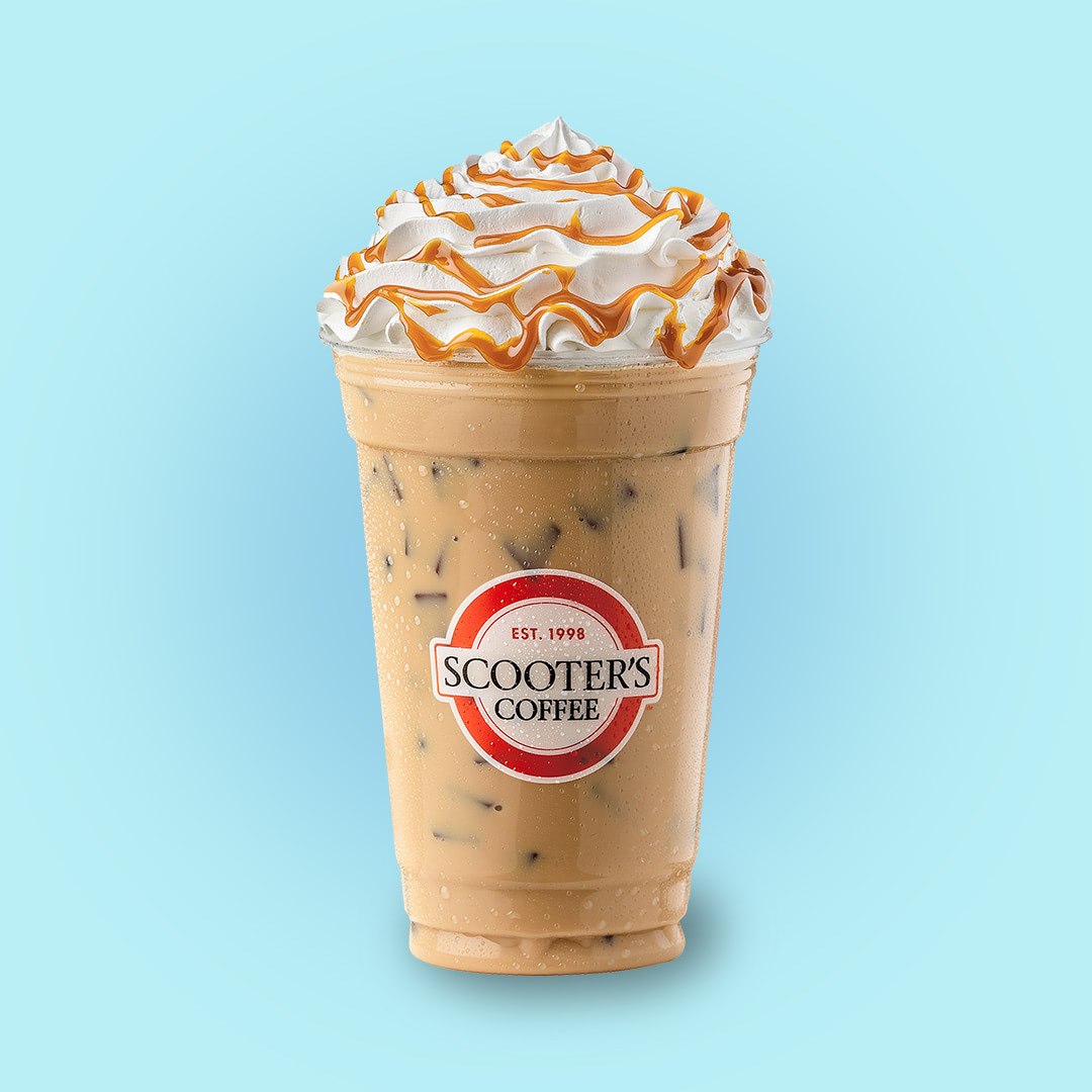 Iced coffee drink topped with whipped cream and caramel drizzle on blue background