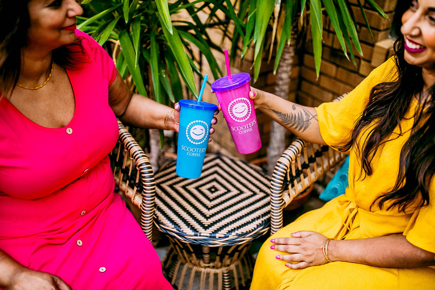 Two women smiling holding blue and pink color changing cups