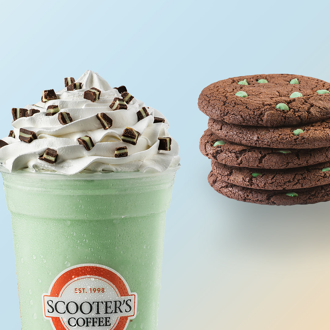 Green blended drink topped with whipped cream next to chocolate mint cookie